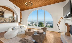 Legacy Healing Center, Wattles – A spacious luxury treatment center common area featuring a large arched window with panoramic city views, comfortable seating, warm wood ceilings, and natural light, designed to support healing and recovery in a serene environment.