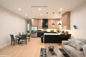 Legacy Healing Center Cleon, Los Angeles – A modern open-concept kitchen and living area with wood cabinetry, stainless steel appliances, pendant lighting, dining table, and comfortable seating designed to provide a supportive and home-like environment during addiction treatment.