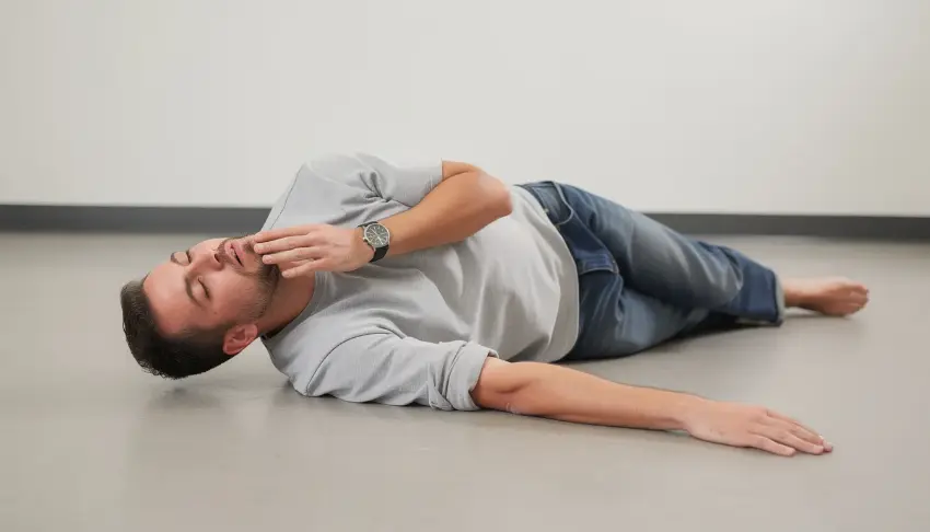 The image shows a person lying on their side in the recovery position on the floor, a crucial step in responding to an opioid overdose. This position helps maintain an open airway and can be vital in preventing fatal overdose, especially when naloxone is administered, especially for when users are trying to understand does narcan work on fentanyl.