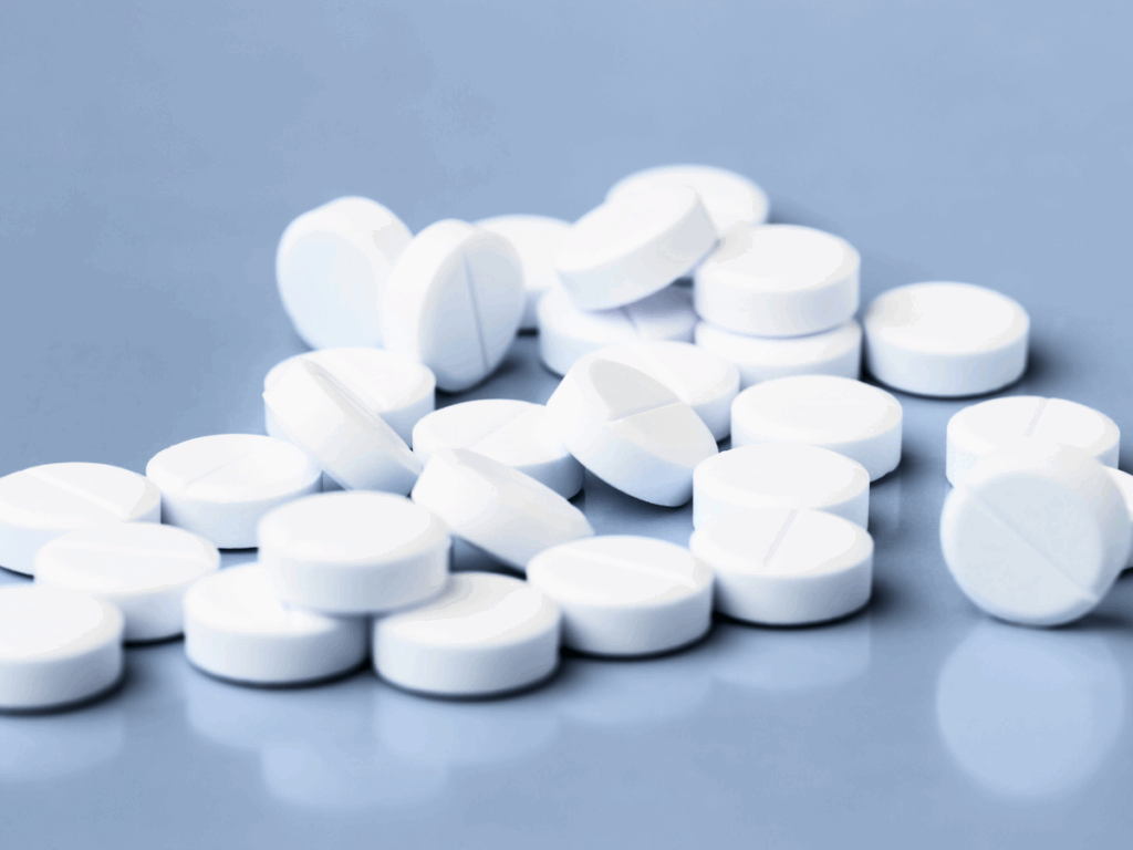 White amphetamine tablets on a blue surface representing addiction, withdrawal, and medical detox treatment.