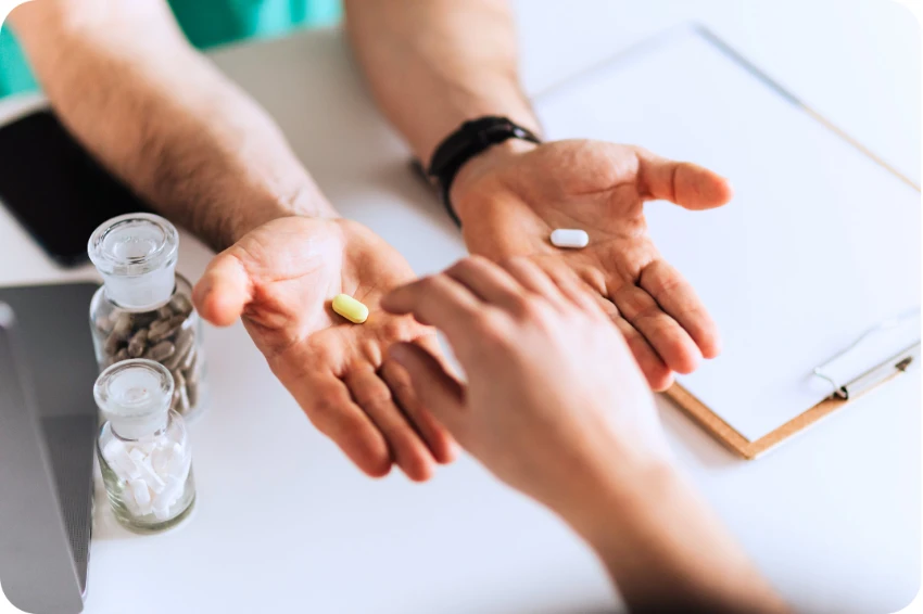 A doctor holding a yellow pill and a white pill in their open palms, presenting options to a patient during a consultation for Suboxone or Sublocade treatment.